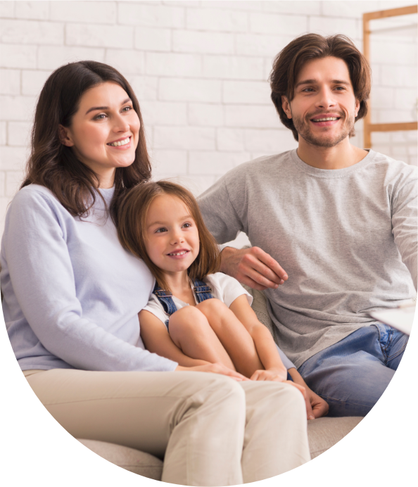 Smiling parents with young daughter sitting together at home