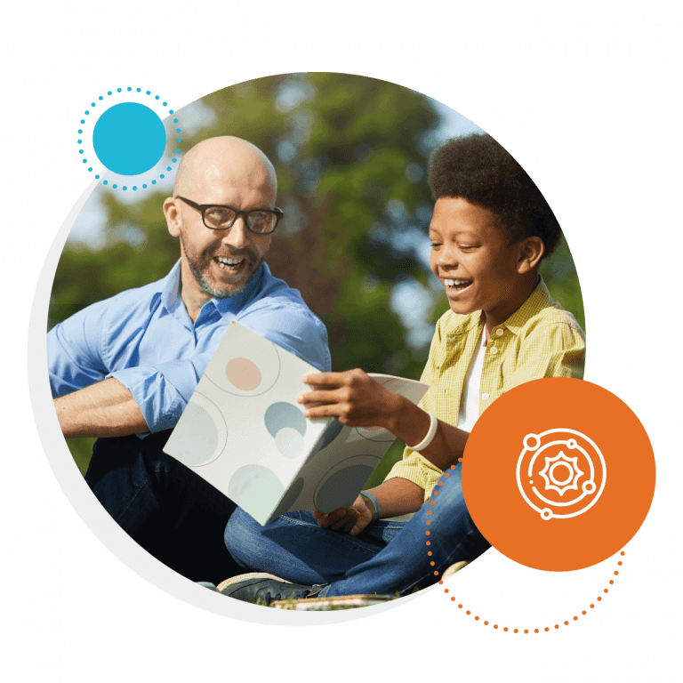 Enfant souriant lisant un livre avec l’aide d’un adulte en plein air