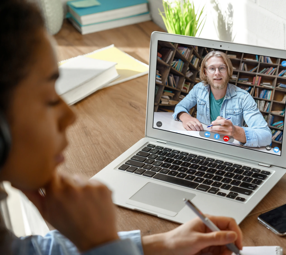 Étudiante assistant à un cours en visioconférence avec un professeur en ligne