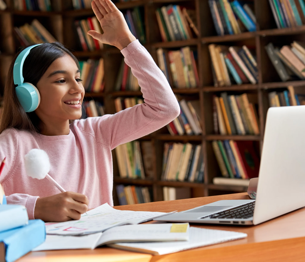 Jeune élève en visioconférence scolaire, levant la main avec casque audio et ordinateur portable